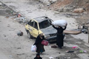 Women carry their belongings as they wait to be evacuated from a rebel-held sector of eastern Aleppo