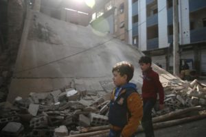 Boys walk near a damaged building in the rebel held besieged city of Douma, in the eastern Damascus suburb of Ghouta