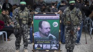 Members of the Izz ad-Din al-Qassam Brigades, the military wing of Hamas, hold a banner bearing a portrait of one of their leaders, Mohamed al-Zoari, who was killed in Tunisia, during a ceremony in his memory on December 18, 2016, in Gaza City.