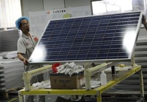 A worker lifts a solar panel in the Yingli Solar factory