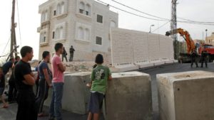 Palestinians watch a wall being built between Palestinian and Jewish neighborhoods in Jerusalem Sunday, Oct. 18, 2015.