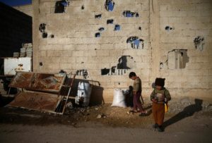 Boys stand in front of a damaged wall in the rebel held besieged Douma neighbourhood of Damascus, Syria January 17, 2017. REUTERS/Bassam Khabieh