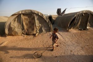 FILE PHOTO: An internally displaced Syrian boy plays with a wheel in Jrzinaz camp