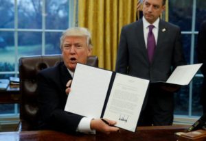 U.S. President Donald Trump holds up the executive order on withdrawal from the Trans Pacific Partnership after signing it as White House Chief of Staff Reince Priebus stands at his side in the Oval Office of the White House in Washington January 23, 2017. REUTERS/Kevin Lamarque