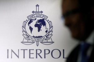 A man passes an Interpol logo during the handing over ceremony of the new premises for Interpol's Global Complex for Innovation, a research and development facility, in Singapore September 30, 2014. REUTERS/Edgar Su/File Photo