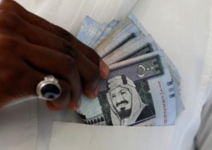 A Saudi man shows Saudi riyal banknotes at a money exchange shop in Riyadh
