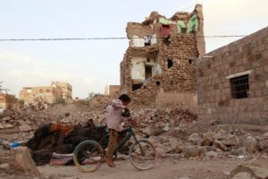 A boy rides a bike through the rubble Yemen in March 2015
