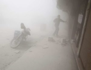 A Syrian man runs for cover amid the dust and smoke following a reported regime air strike on the rebel-controlled town of Hamouria, in the eastern Ghouta region on the outskirts of the capital Damascus, on April 3, 2017.
