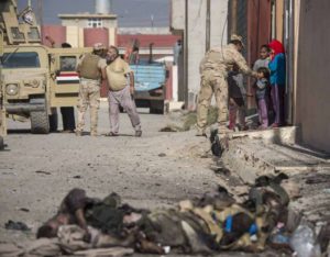 Bodies of ISIS fighters lie on a street in Mosul's eastern Al-Intissar neighborhood as Iraqi soldiers talk to residents.