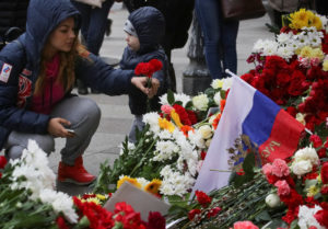 A woman places flowers at a memorial site for the victims of a blast in St. Petersburg metro, outside Tekhnologicheskiy Institut metro station in St. Petersburg
