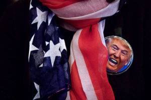Flag scarf and button on a Donald Trump supporter at a campaign event.