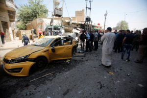 People gather at the site of car bomb attack near a government office in Karkh district in Baghdad