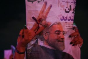 Supporter of Iranian president Hassan Rouhani holds his poster as she celebrates his victory in the presidential election, in Tehran