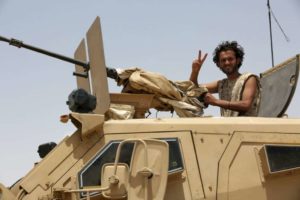 A soldier gestures as he sits atop a military vehicle accompanying Gulf Arab soldiers while they arrive at Yemen's northern province of Marib