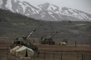 Israeli soldiers walk near mobile artillery units near the border with Syria in the Golan Heights
