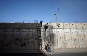 Palestinians climb over a section of the controversial Israeli barrier as they try to make their way to attend the second Friday prayers of Ramadan in Jerusalem's al-Aqsa mosque, near Ramallah