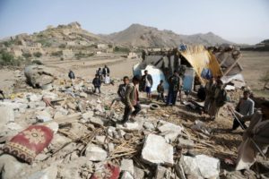 People gather on the wreckage of a house destroyed by an air strike in the Bait Rejal village west of Yemen's capital Sanaa