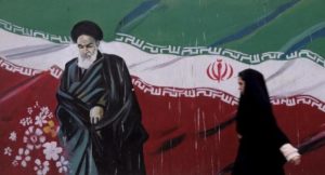 Woman walks past a painting of Iran's late leader Ayatollah Ruhollah Khomeini in Tehran