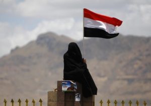 A woman holds the national flag during a parade at a celebration by anti-government protesters commemorating the anniversary of Yemen's reunification, in Sanaa