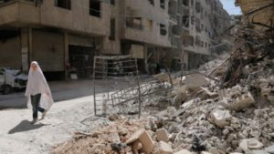 A girl walks past the rubble of a destroyed building down a street in the rebel-held Syrian town of Ayn Tarma, in the Ghouta area east of the capital Damascus, July 19, 2017.