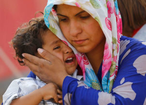 A Syrian Kurdish refugee comforts her child after they crossed into Turkey, fleeing fighting around Kobani, Syria,