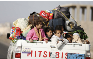 Children ride on the back of a pick-up truck as they flee Sana'a on April 6, 2015