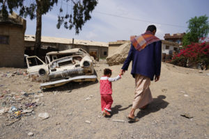 In the Harat Al-Masna’a slum in Sana’a, Yemen, a man walks with his three-year-old daughter which sits next to a former textile factory and hosts 231 families of former factory workers.