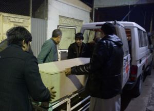 Afghan men unload a coffin of killed ICRC employee from a car at a hospital in Mazar-i-Sharif