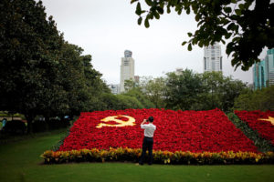 A man takes photos of a party flag of Communist Party of China made with flowers, which promotes the 19th National Congress of the Communist Party of China, in Shanghai